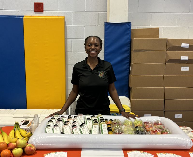Shardai behind a display of cold pressed juice and fruit cups